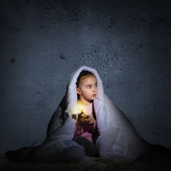 image of a frightened girl under the covers with a flashlight