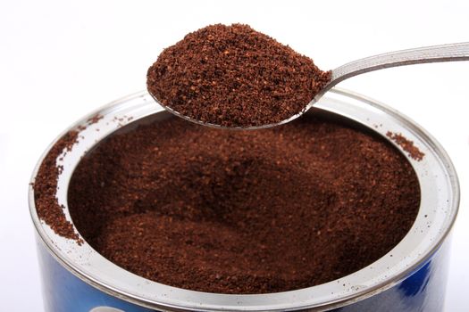 Spoonfull of fresh ground coffee in a can on a white background