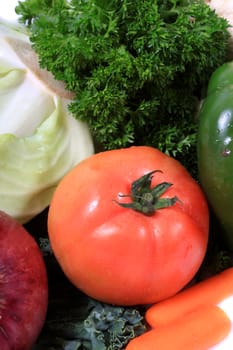 Colorful red tomato surrounded by green vegetables such as cabbage and parsley