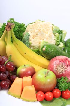 Group of colorful fruits and vegetables like grapes, apples, bananas, and cauliflower