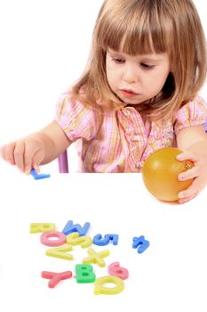 Young girl holding an orange playing with letters and numbers for early childhood development