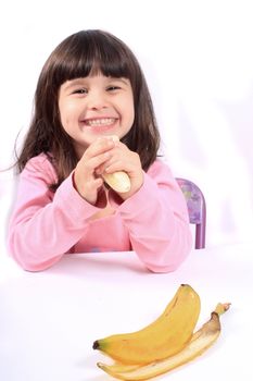 Young little girl smiling eating a healthy banana