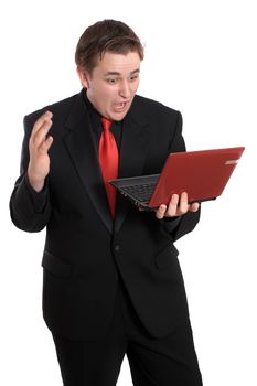 Handsome young businessman holding small computer laptop with a shocked expression on white background