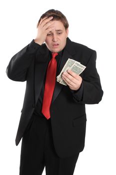 Attractive young man in black suit holding one dollar bills on a white background with shocked expression showing financial loss