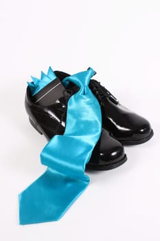 Mens shiny lace up formal black shoes with light blue tie on a white background