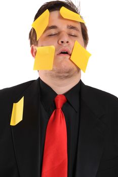 Tired and overwhelmed from work, businessman with yellow sticky note paper on face and suit on a white background