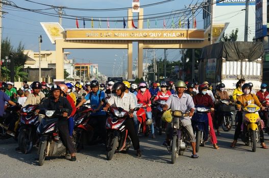 LONG AN, VIET NAM- NOV 11: Crowd of people wear helmet, ride motorbike waiting traffice signal to go to work at morning in Long An, VietNam on Nov 11, 2013