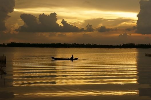 People rowing the row boat on golden surface water of river at sunrise, clouds reflect on water make a rectangle frame   