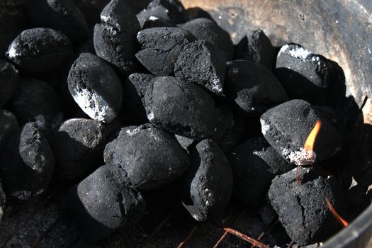 Lighting charcoal in a barbecue showing coals turning white and flame