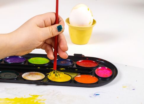 Little girls hands playing with colorful paint, creating Easter decoration