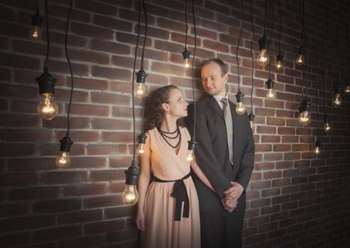 loving couple in the background of walls from a brick and light bulbs