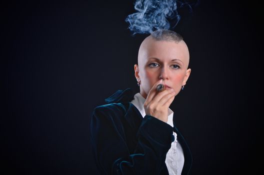 Bald young woman smoking cigar in studio