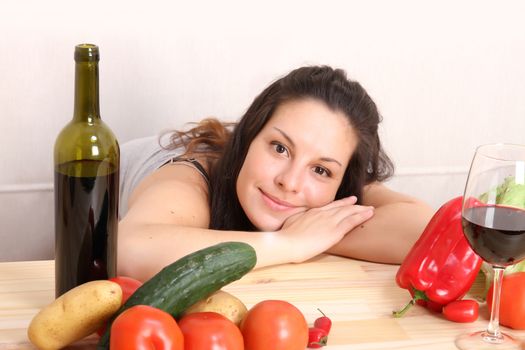 A young hispanic girl in the kitchen between vegetables.