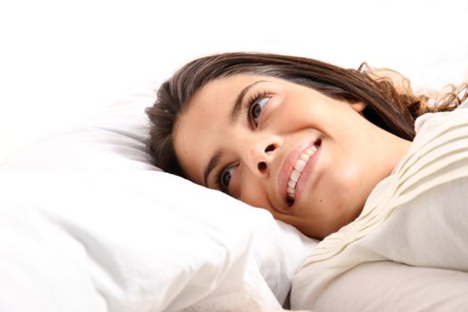 A young girl laying in bed and smiling
