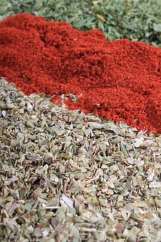 Close up of three different spices, being paprika, parsley flakes and oregano in the front with shallow depth of field