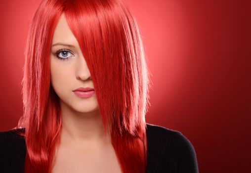 Beautiful red haired woman posing over red background