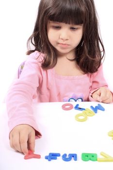 Young little preschool girl with funny expression playing with letters and numbers