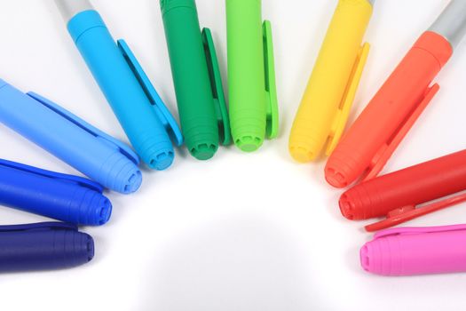 Colorful rainbow markers in blue, green, yellow and reds on a white background