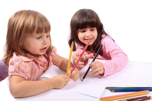 Two little preschool girls drawing with colorful pencil crayons