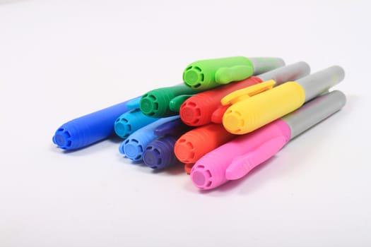 Colorful rainbow markers in blue, green, yellow and reds on a white background