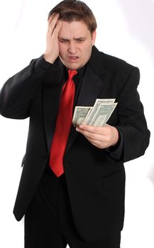 Attractive young man in black suit holding one dollar bills on a white background with shocked expression showing financial loss (focux on money)