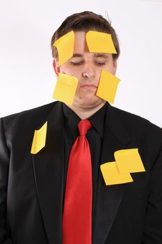 Bored and overwhelmed from work, businessman with yellow sticky note paper on face and suit on a white background