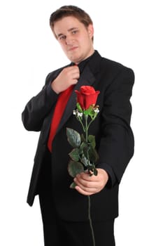 Handsome young man wearing a formal suit  holds and offers you a rose on a white background