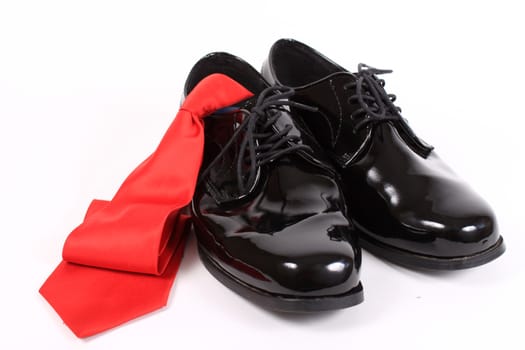 Mens shiny lace up formal black shoes with red tie on a white background