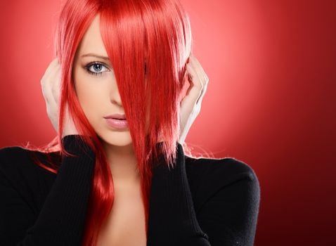 Beautiful red haired woman posing over red background