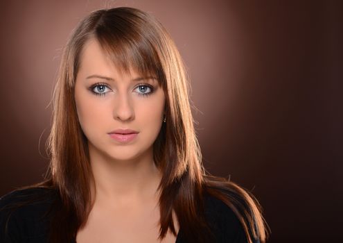 Beautiful brown haired woman posing over brown background