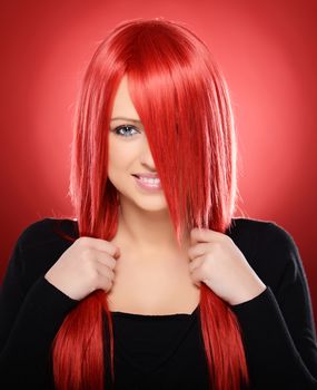 Beautiful red haired woman posing over red background