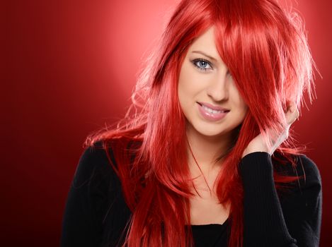 Beautiful red haired woman posing over red background
