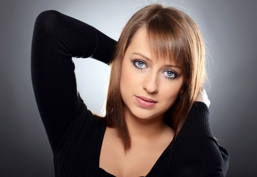 Beautiful brown haired woman posing over grey background