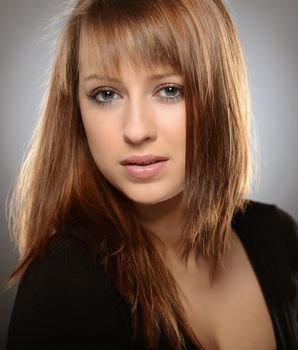 Beautiful brown haired woman posing over grey background