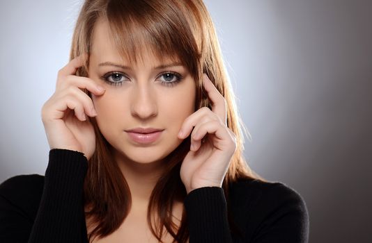 Beautiful brown haired woman posing over grey background