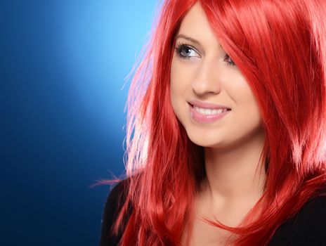 Beautiful red haired woman posing over blue background