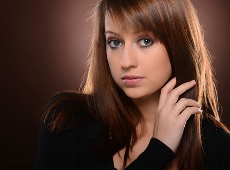 Beautiful brown haired woman posing over brown background