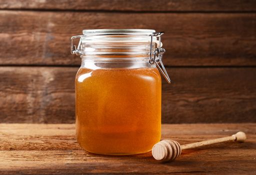 Fresh honey in glass jar on wooden background