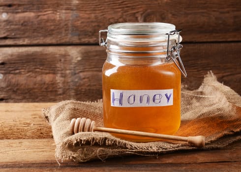 Fresh honey in glass jar on wooden background