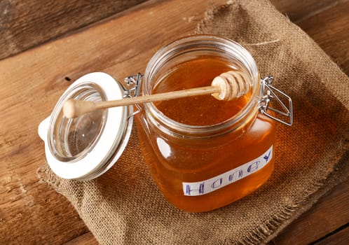 Fresh honey in glass jar on wooden background