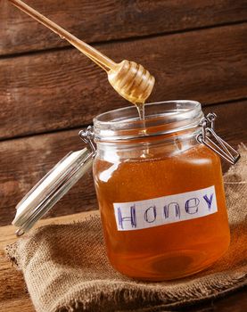 Fresh honey in glass jar on wooden background