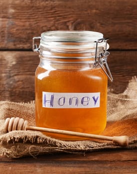 Fresh honey in glass jar on wooden background