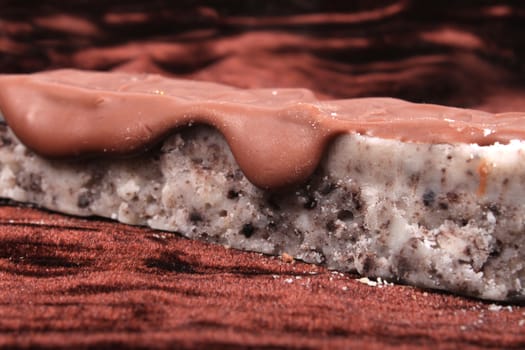 Close up of cookie crumble fudge bar drizzled with chocolate on a brown velvet  background