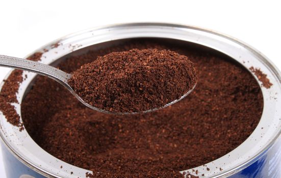 Spoonfull of fresh ground coffee in a can on a white background