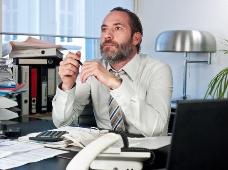 Contemplative businessman looking away at work. Horizontal shot