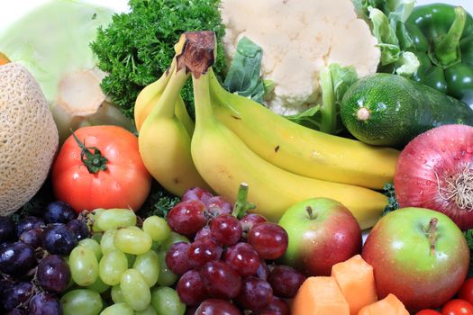 Group of colorful fruits and vegetables like grapes, apples, bananas, and cauliflower