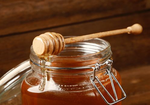 Fresh honey in glass jar on wooden background