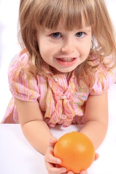 Cute little blonde girl holding a healthy orange and smiling