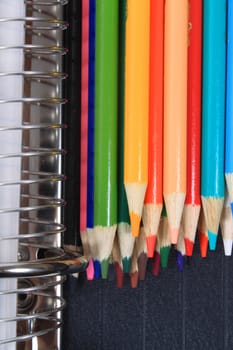 Colorful sharpened  pencil crayons for school  beside  three ring binder 