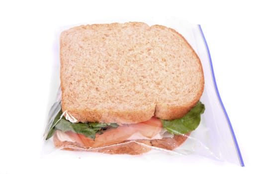 Turkey and cheese sandwich on whole wheat bread with tomato and lettuce inside a zipped bag ready for lunch